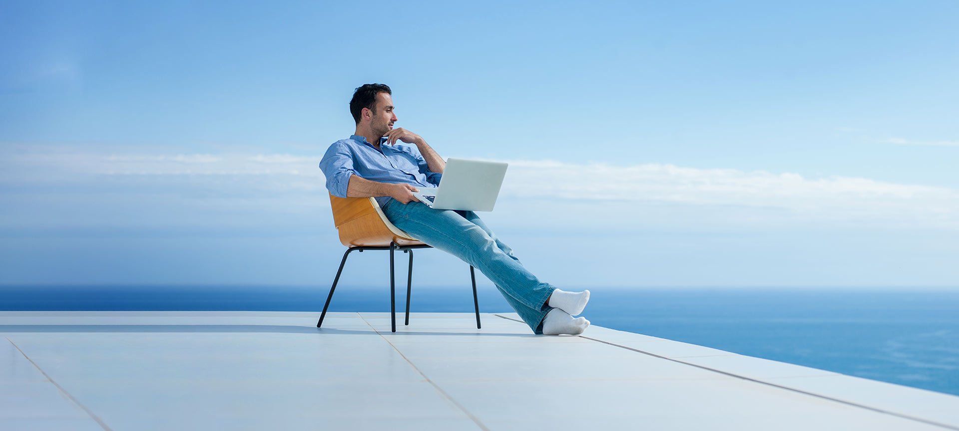 Homme travaillant sur un ordinateur portable avec vue sur la mer Homme travaillant sur un ordinateur portable avec vue sur la mer