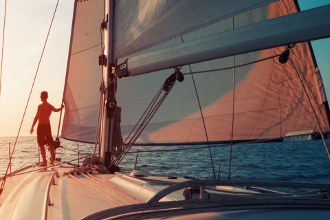 Boy in a sailing boat at sunset