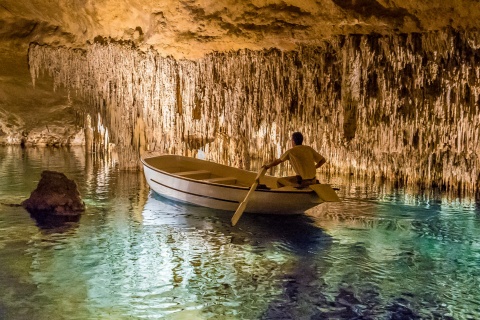 Homem numa lancha no interior das Cuevas del Drach (cavernas do dragão), em Maiorca.