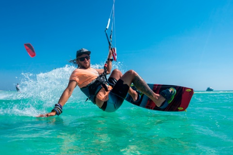 Jovem praticando kite em águas cristalinas