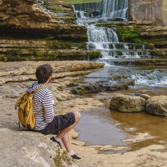 Tourist betrachtet den Bolao-Wasserfall in Toñanes, Kantabrien