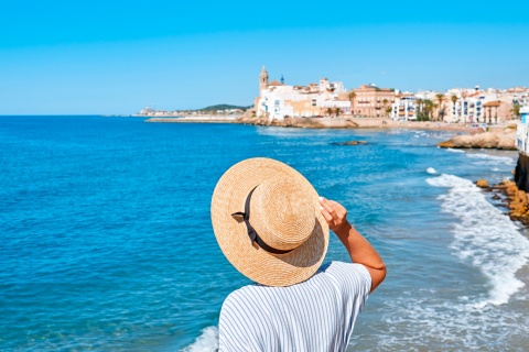 Frau mit Blick auf das Meer und die Kirche Sant Bartomeu in Sitges