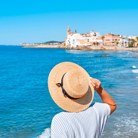 Mujer contemplando el mar y la iglesia de Sant Bartomeu en Sitges