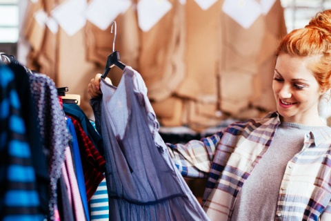 Junge Frau sieht sich beim Shoppen ein Kleid an