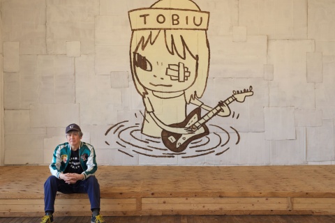 Yoshitomo Nara sentado na frente de TOBIU, 2019. Doação do artista ao leilão TWO x TWO for AIDS and Art, 2021. Cortesia do artista, Blum & Poe e Pace Gallery