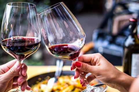 Toasting with red wine and a paella in the background