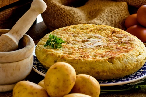 Spanish omelette with products to make it and a mortar