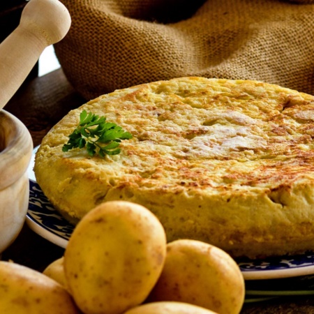 Tortilla de pommes de terre avec ses ingrédients et un mortier