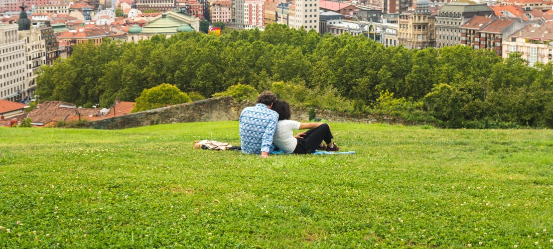 Pareja viendo una hermosa vista panorámica de la ciudad sentada en el parque de la colina sobre el Casco Antiguo