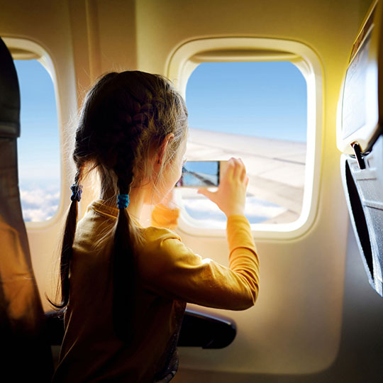 Niña haciendo foto por la ventanilla de un avión