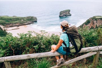  Peregrina sentada con vistas a la costa en el Camino del Norte