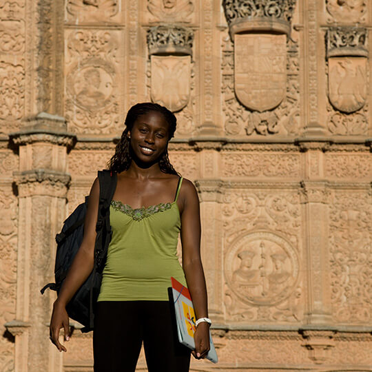 Estudante em frente à fachada da Universidade de Salamanca