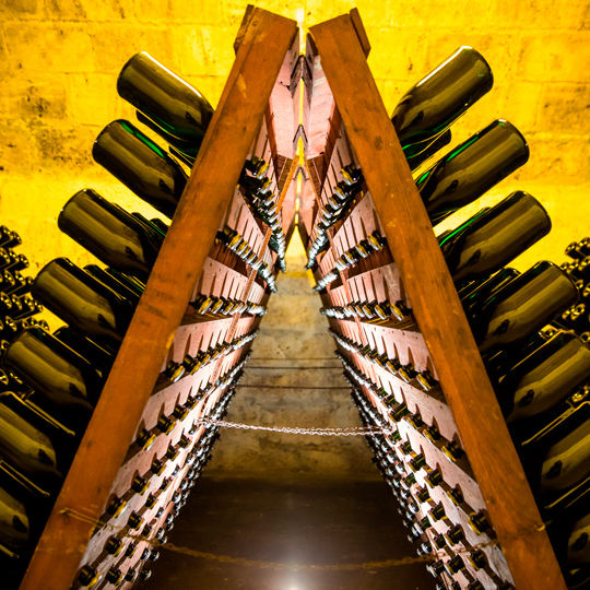 Botellas de cava reposando en pupitres de madera