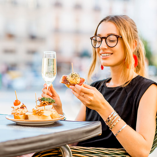 Moça jovem comendo tapas em um terraço de Valência.