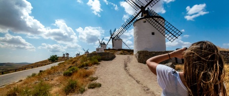 Une jeune fille photographiant les moulins à vent à Consuegra, province de Tolède