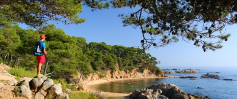 Hiker on the Camí de Ronda trail looking out on Cala Estreta de Palamós in Girona, Catalonia