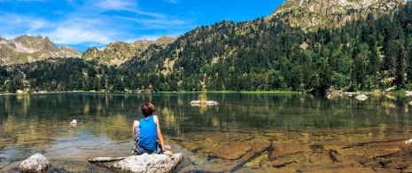 Niño sentado en uno de los lagos del Parque Nacional de Aigüestortes i Estany de Sant Maurici en Lérida, Cataluña