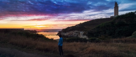 Menina contemplando o pôr do sol perto da Torre de Hércules, Galiza