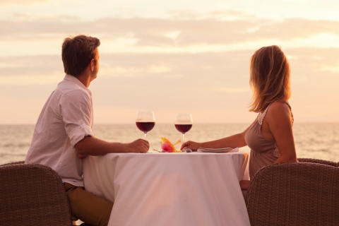 Pareja compartiendo una copa de vino frente al mar