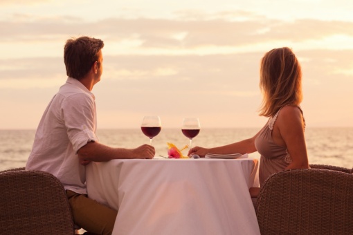 Coppia che condivide un bicchiere di vino sul mare