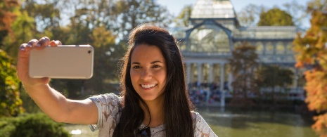 Mujer haciéndose un selfie frente al Palacio de Cristal en Madrid, Comunidad de Madrid