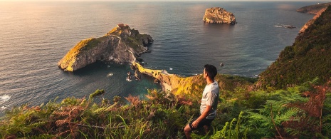 Turista che ammira San Juan de Gaztelugatxe a Biscaglia, Paesi Baschi