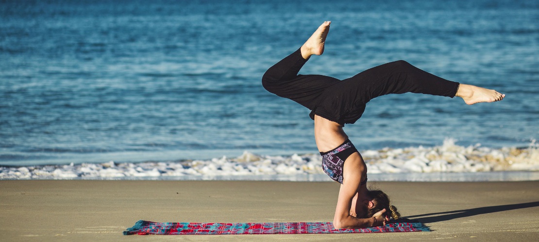 Chica practicando yoga en la playa