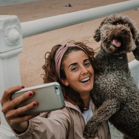 Turista sacándose un selfie con su mascota en una playa de Gijón, Asturias