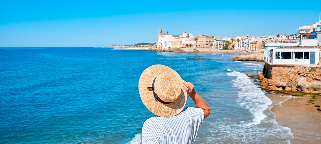 Mulher contemplando o mar e a igreja de Sant Bartomeu em Sitges
