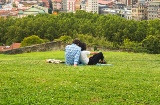 Couple watching a beautiful panoramic view of Bilbao sitting in the park on the hill above the Old Town